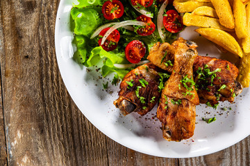 Grilled chicken drumsticks with french fries and vegetables