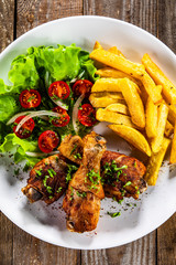 Grilled chicken drumsticks with french fries and vegetables