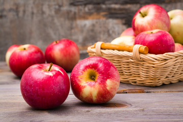 Fresh harvest of apples. Nature theme with red apples in a basket on a wooden background. Fruit nature concept.