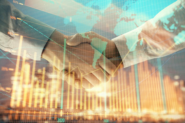 Double exposure of financial chart and world map on cityscape background with two businessmen handshake. Concept of international investment