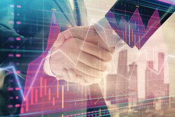 Double exposure of financial graph on cityscape background with two businessman handshake. Concept of stock market deal