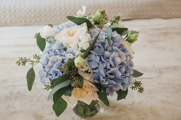 Close-up of a bouquet of flowers - blue Garden Hydrangeas and white Peony Roses in a vase on the table.