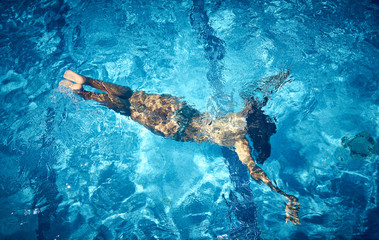 Aerial view of Young woman swimming underwater in the pool