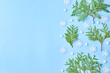 Obraz premium Flat lay christmas border with snowflakes and evergreen tree branch on a blue background