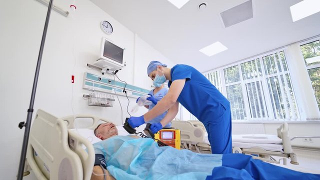 Emergency room procedures. Medical team performing defibrillation on a patient in modern operating room. Medical equipment.