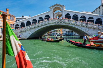 Italian maritime flag with Rialto bridge with gondolas in the bacground. Grand Canal, Venice, Italy