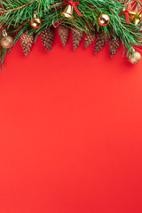 Christmas concept with pine branches with cones and other holiday decorations. Flat lay composition on red background. Top view and copy space for text