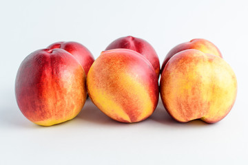 Six fresh ripe nectarine fruits displated as on two lines on a white table, isolated on white, with soft focus, side view