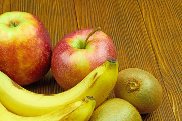 Close up view of red apples, bananas and kiwi on wooden background. Still life of fresh fruits