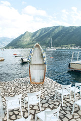 A wooden boat decorated with flowers as a wedding arch on the background of the sea. Preparing for the wedding.