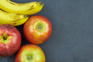 Fresh fruits. Top view of red apples and bananas on dark background with copy space for text