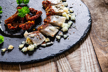 Marinated herring fillets on black stone
