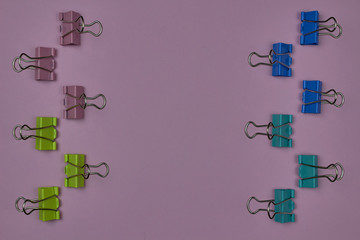 Pink, yellow, blue and green paper clips on a pink background with copy space for text