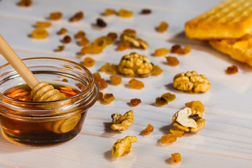 Bowl with honey and core walnuts on white wooden table
