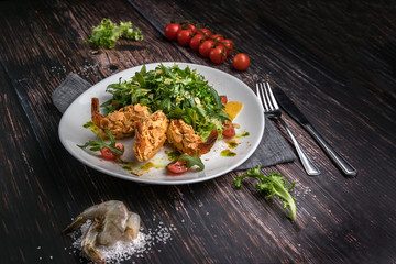Fresh salad plate with shrimp, tomato, arugula, orange on wooden dark background close up. Healthy food concept in rustic style