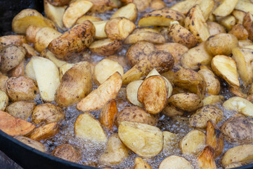 Roast potatoes in a large pan.Young potatoes are fried in oil, street food
