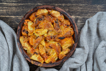 Baked potato and carrot with cheese on the wooden table, close up. Ceramic bowl with potato and carrot slices background