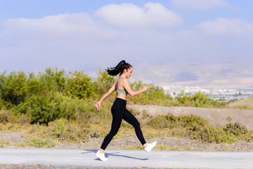 Side view young female runner jumping outdoors