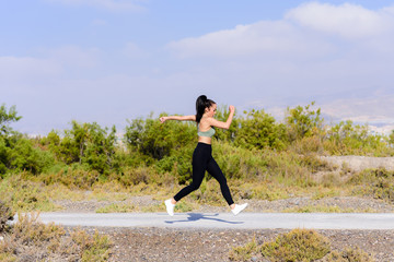 Side view young female runner jumping outdoors