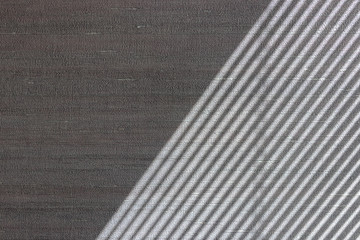 Hard diagonal shadows on grey textured wall from a window roller shutter or blinds. Attractive...