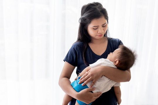 Asian Mother Standing And Carry A 1 Year Old Son Who Sleeping In Her Arms With Love, Relationship And Happiness To Take Care Of Children, With White Background, To Family And Mother's Day Concept.