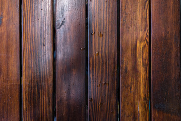 Dark brown boards background with spots. Old wet wood texture pattern after rain with reflections