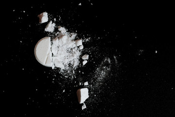 White squashed tablet pill on black background. Top view - obrazy, fototapety, plakaty