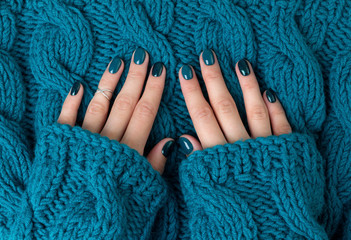 Manicured woman's hands in warm wool turquoise sweater