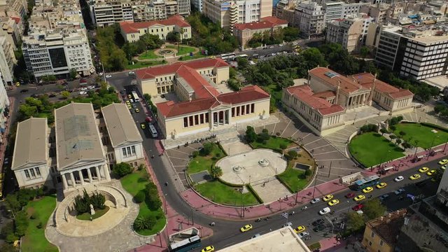 Aerial video of famous trilogy landmark buildings of Academy of Athens, Panepistimio or University, public Library with iconic Lycabettus hill at the background, Athens, Attica, Greece