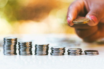 Woman raises coin stack on blurred background and copy space - - Economy Concept - Financial and...