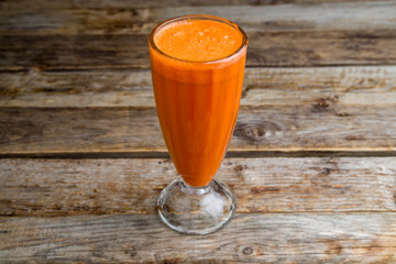 Fresh carrot in a glass on a wooden background
