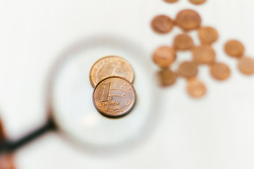Real one cent coin seen through a magnifying glass - coins on table - economy and finance concept.