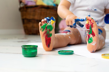 Little cute girl draws with finger paints on the floor. Early development concept