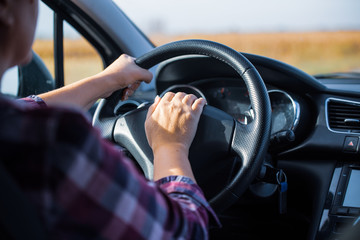 a young woman holds her hands on the wheel while driving