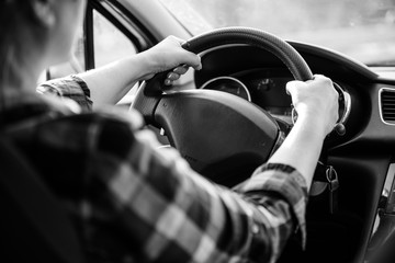 a young woman holds her hands on the wheel while driving