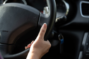 a young woman holds her hands on the wheel while driving