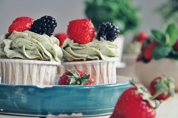 Strawberry cupcakes and green leaves on wooden background