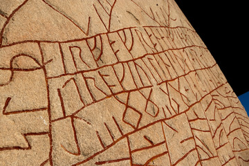Close up of a Swedish rune stone with red runes 