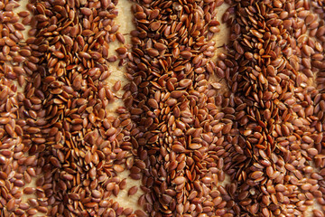 Obraz premium Brown flax seeds give flaxseed oil background
