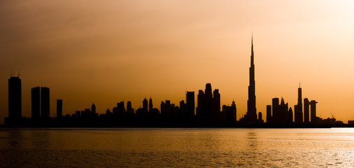 Fototapeta na wymiar Stunning view of the silhouette of the Dubai skyline during a beautiful and dramatic sunset. Dubai is the largest and most populous city in the United Arab Emirates (UAE)