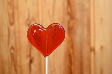 Red heart shape lollipop against blurred wooden background. Love, Saint Valentine's days concept
