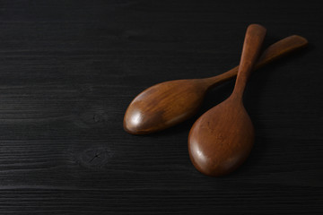 Brown wooden spoons on black wood background. Copy space