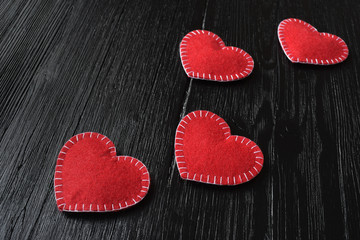 Obraz na płótnie Canvas Red felt handmade hearts on black wooden surface. Valentines day background.