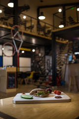 Appetizing fast food on a wooden board with fresh vegetables.