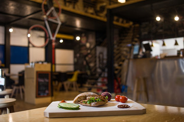 Appetizing fast food on a wooden board with fresh vegetables.