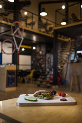 Appetizing fast food on a wooden board with fresh vegetables.