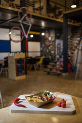 Appetizing fast food on a wooden board with fresh vegetables.