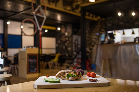 Appetizing fast food on a wooden board with fresh vegetables.