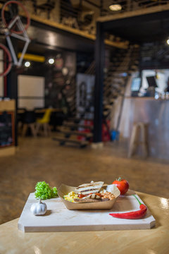 Appetizing fast food on a wooden board with fresh vegetables.