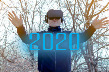 The concept of the holiday of 2020, a young man with virtual reality glasses, a caucasian male with...